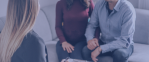 An anonymous couple sitting on the grey sofa, holding hands and going through private counselling.